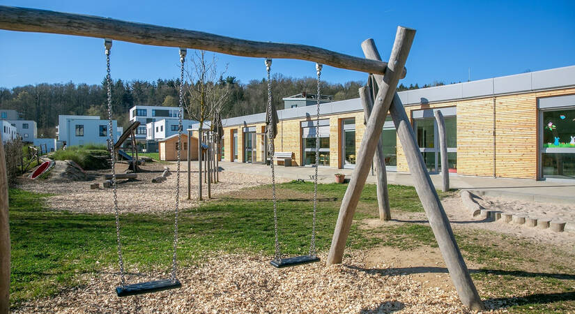 Blauer Himmel über dem Außenbereich eines Kindergartens mit Schaukel und Rutsche