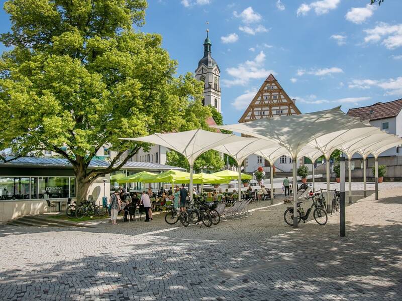 Schirme schützen vor Sonnenschein Radfahrer und andere Gäste im Café